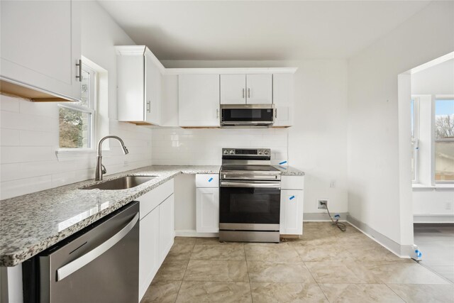 102 Glendale St, Houston, TX 77012 - kitchen with appliances with stainless steel finishes, decorative backsplash, light stone countertops, and white cabinets