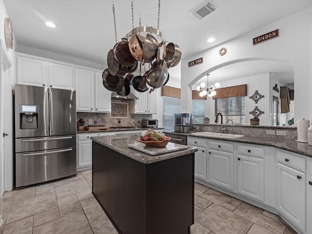 11938 Galentine Pt, Cypress, TX 77429 - kitchen with stainless steel appliances, a chandelier, backsplash, arched walkways, and white cabinetry