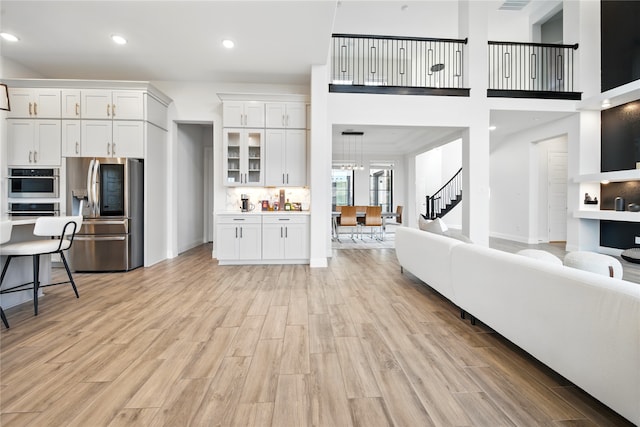 18011 Brazos River Cir, Cypress, TX 77433 - living room featuring light wood-style flooring, stairway, recessed lighting, and a towering ceiling