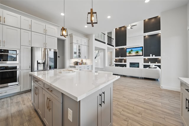 18011 Brazos River Cir, Cypress, TX 77433 - kitchen featuring appliances with stainless steel finishes, light wood-type flooring, a center island, open floor plan, and pendant lighting