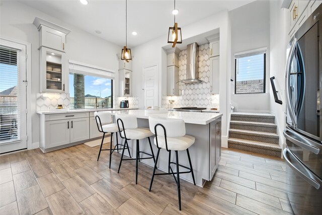 18011 Brazos River Cir, Cypress, TX 77433 - kitchen featuring freestanding refrigerator, wall chimney range hood, a kitchen breakfast bar, light countertops, and a kitchen island