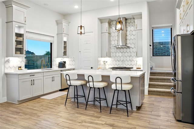 18011 Brazos River Cir, Cypress, TX 77433 - kitchen featuring freestanding refrigerator, dishwashing machine, wall chimney range hood, backsplash, and a kitchen breakfast bar