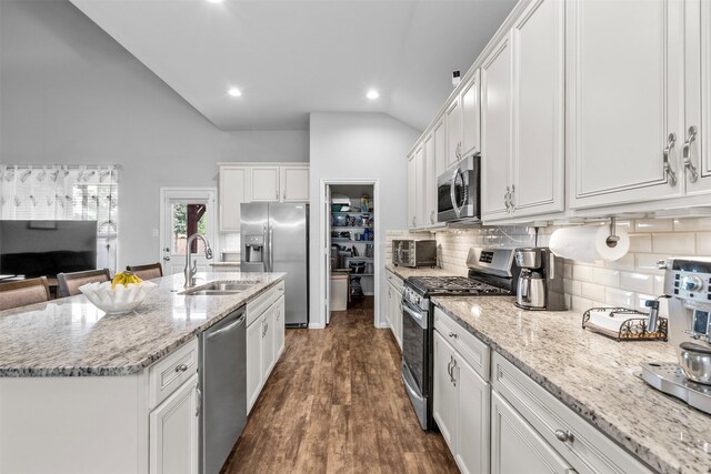 12137 Pearl Bay Ln, Conroe, TX 77304 - kitchen with stainless steel appliances, white cabinetry, backsplash, dark wood-style floors, and a center island with sink