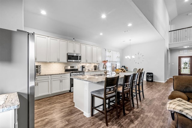 12137 Pearl Bay Ln, Conroe, TX 77304 - kitchen with stainless steel appliances, dark wood-type flooring, backsplash, a kitchen bar, and white cabinets