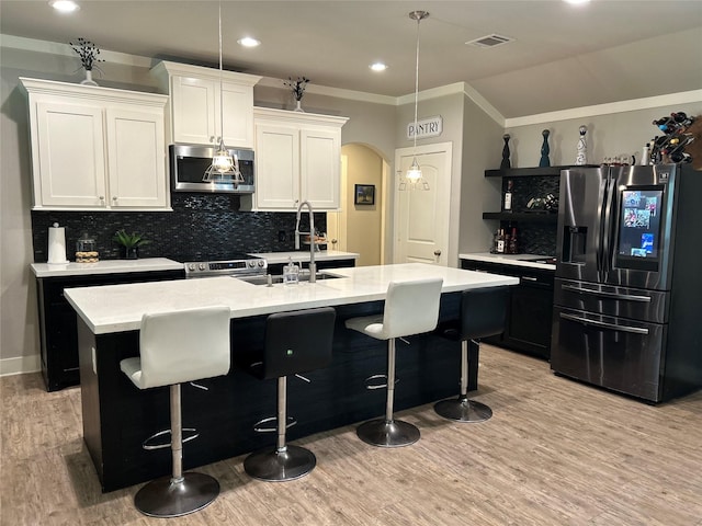 23918 Overcup Dr, Spring, TX 77389 - kitchen featuring appliances with stainless steel finishes, arched walkways, light countertops, light wood-style floors, and tasteful backsplash
