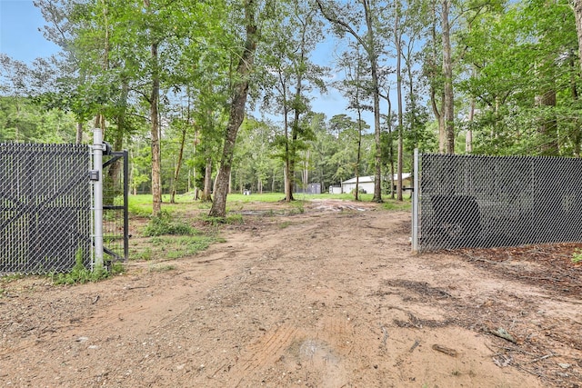 24824 W Christine Dr, Splendora, TX 77372 - view of dirt / gravel road featuring a gated entry and view of scattered trees