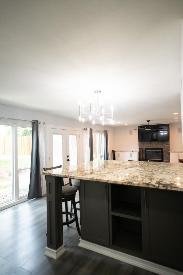 17106 Spring Creek Forest Dr, Spring, TX 77379 - kitchen with light stone countertops, dark wood-style flooring, a large fireplace, a chandelier, and hanging light fixtures