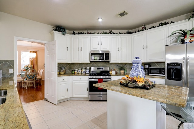 4714 Schiller Park Ln, Sugar Land, TX 77479 - kitchen featuring stainless steel appliances, a chandelier, white cabinetry, light stone countertops, and recessed lighting