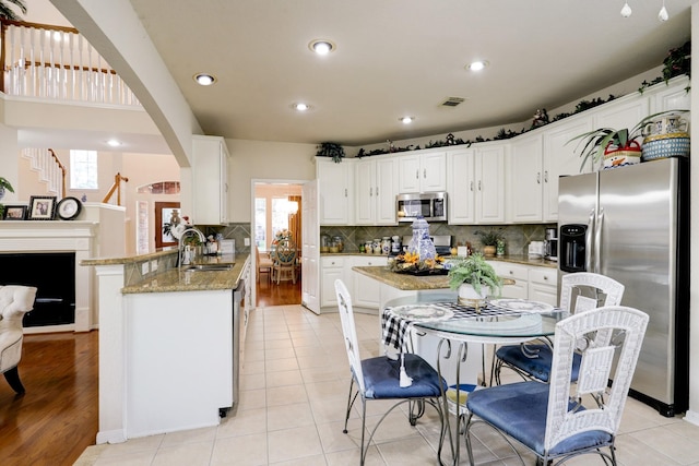 4714 Schiller Park Ln, Sugar Land, TX 77479 - kitchen with stainless steel appliances, plenty of natural light, white cabinets, a peninsula, and recessed lighting