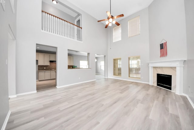 6803 Chapelfield Ln, Houston, TX 77049 - unfurnished living room with ceiling fan, a towering ceiling, a fireplace, and light wood-type flooring