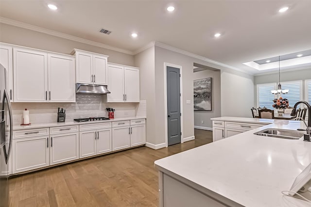 1939 Heather Canyon Dr, Pearland, TX 77089 - kitchen with under cabinet range hood, gas cooktop, recessed lighting, white cabinets, and tasteful backsplash
