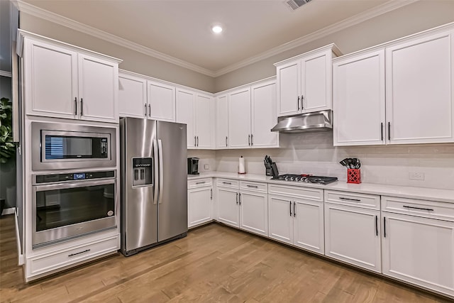 1939 Heather Canyon Dr, Pearland, TX 77089 - kitchen with stainless steel appliances, under cabinet range hood, light countertops, ornamental molding, and white cabinetry