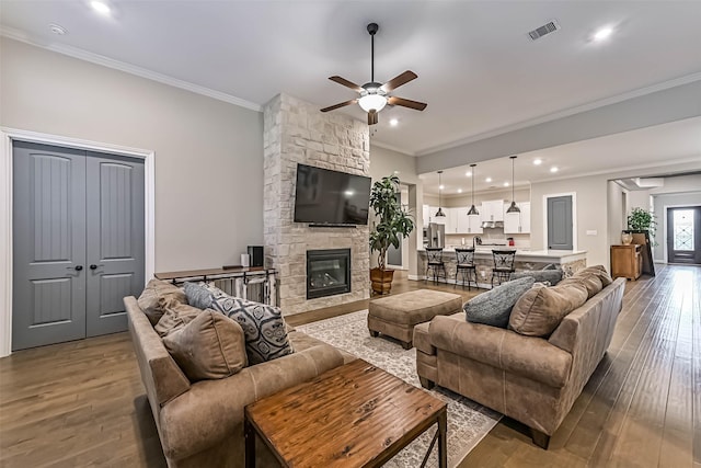 1939 Heather Canyon Dr, Pearland, TX 77089 - living area with ceiling fan, ornamental molding, dark wood finished floors, recessed lighting, and a stone fireplace