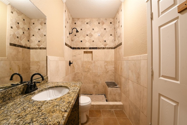 6709 Jay Rd, Hitchcock, TX 77563 - full bathroom with tile walls, tiled shower, vanity, tile patterned floors, and a textured ceiling