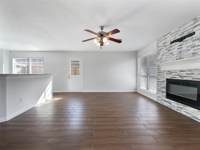 2317 Shady Pine Dr, Conroe, TX 77301 - unfurnished living room featuring ceiling fan, dark wood finished floors, and a stone fireplace