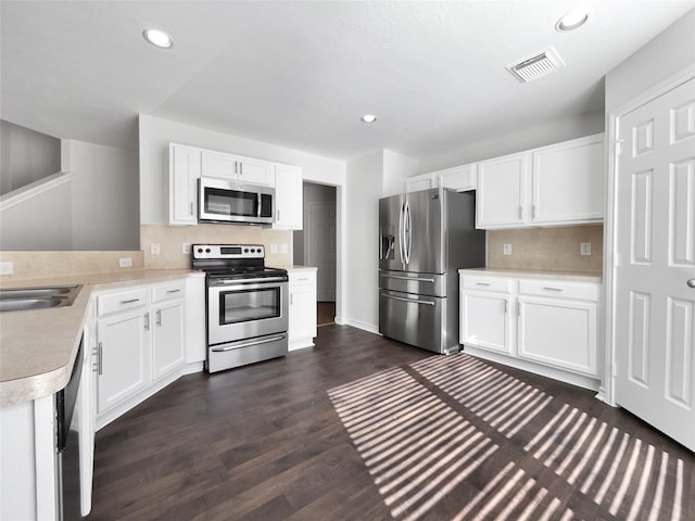 2317 Shady Pine Dr, Conroe, TX 77301 - kitchen featuring stainless steel appliances, light countertops, dark wood-type flooring, white cabinetry, and recessed lighting