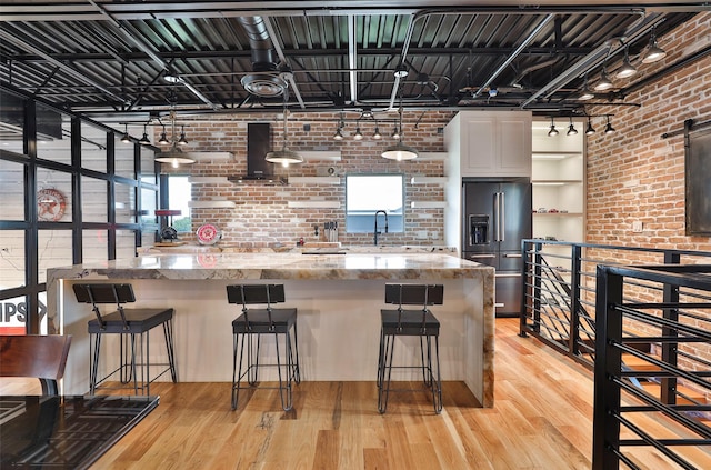 1435 Fm 1463rd Rd Unit C14, Katy, TX 77494 - kitchen with high end refrigerator, wall chimney exhaust hood, brick wall, light wood finished floors, and white cabinets
