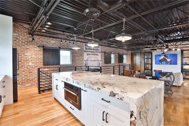1435 Fm 1463rd Rd Unit C14, Katy, TX 77494 - kitchen featuring brick wall, light wood finished floors, white cabinets, oven, and light stone counters