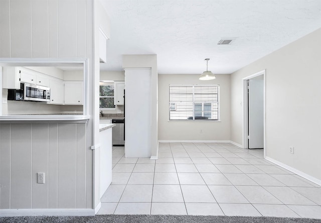 510 Shenandoah Dr, Shenandoah, TX 77381 - kitchen with white cabinets, stainless steel appliances, light tile patterned floors, hanging light fixtures, and light countertops