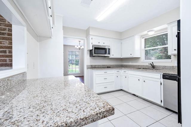 510 Shenandoah Dr, Shenandoah, TX 77381 - kitchen with white cabinets, appliances with stainless steel finishes, light tile patterned floors, a chandelier, and light stone counters