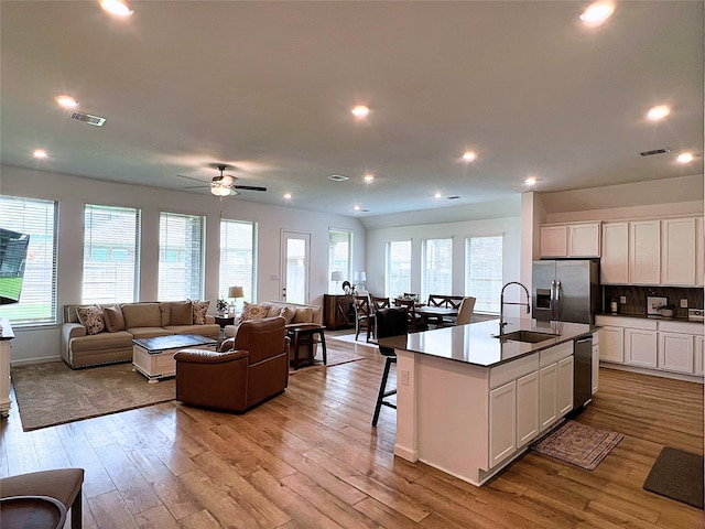 19022 Palizzi Ridge Ln, New Caney, TX 77357 - kitchen featuring stainless steel appliances, open floor plan, light wood-style floors, white cabinetry, and tasteful backsplash