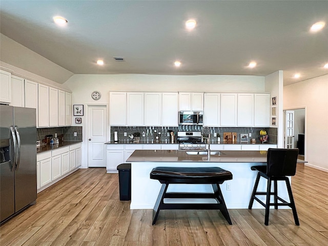 19022 Palizzi Ridge Ln, New Caney, TX 77357 - kitchen featuring appliances with stainless steel finishes, decorative backsplash, white cabinets, a breakfast bar area, and recessed lighting