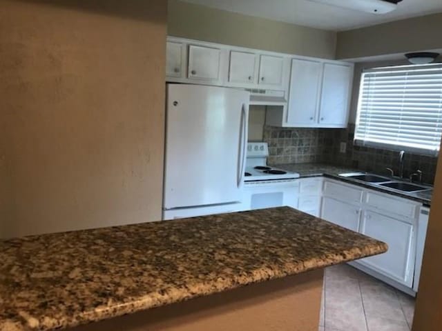 7900 Westheimer Rd Unit 112, Houston, TX 77063 - kitchen featuring white appliances, white cabinetry, decorative backsplash, light tile patterned flooring, and dark stone countertops