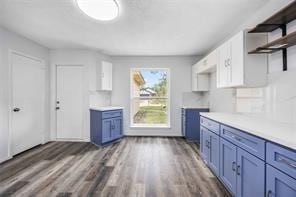 19314 Cypress Arbor Ct, Katy, TX 77449 - kitchen with open shelves, dark wood-style floors, light countertops, blue cabinets, and white cabinets