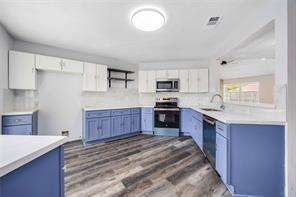 19314 Cypress Arbor Ct, Katy, TX 77449 - kitchen featuring stove, stainless steel microwave, dishwashing machine, blue cabinetry, and white cabinetry