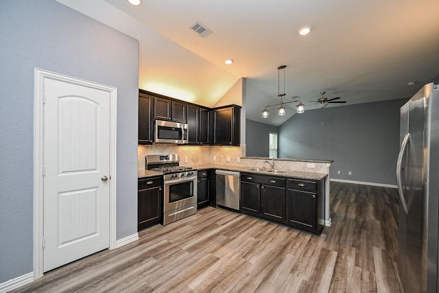 23014 Indigo Prairie Ln, Katy, TX 77493 - kitchen with stainless steel appliances, a peninsula, a ceiling fan, light wood-style floors, and tasteful backsplash
