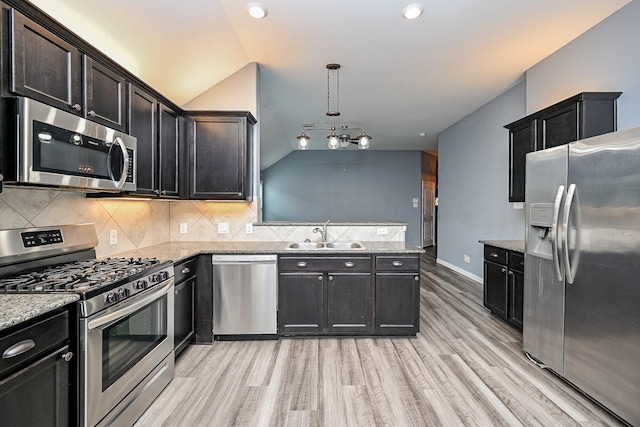 23014 Indigo Prairie Ln, Katy, TX 77493 - kitchen featuring appliances with stainless steel finishes, light wood-style flooring, decorative backsplash, a peninsula, and vaulted ceiling