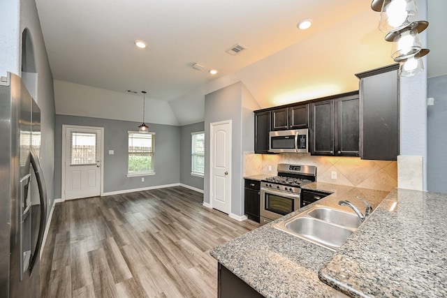 23014 Indigo Prairie Ln, Katy, TX 77493 - kitchen featuring stainless steel appliances, vaulted ceiling, wood finished floors, backsplash, and light stone countertops