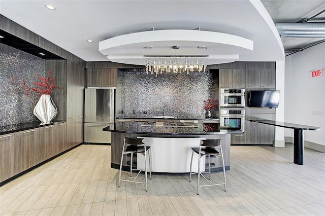 1901 Post Oak Unit 302, Houston, TX 77056 - kitchen with appliances with stainless steel finishes, a kitchen bar, modern cabinets, dark countertops, and backsplash