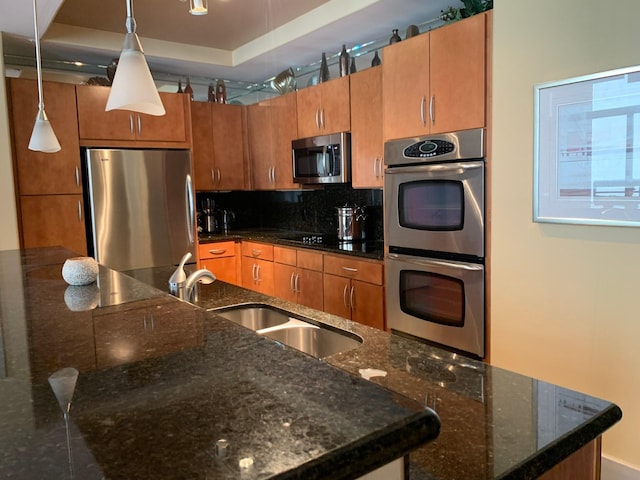 1901 Post Oak Unit 302, Houston, TX 77056 - kitchen featuring appliances with stainless steel finishes, tasteful backsplash, brown cabinetry, hanging light fixtures, and dark stone counters