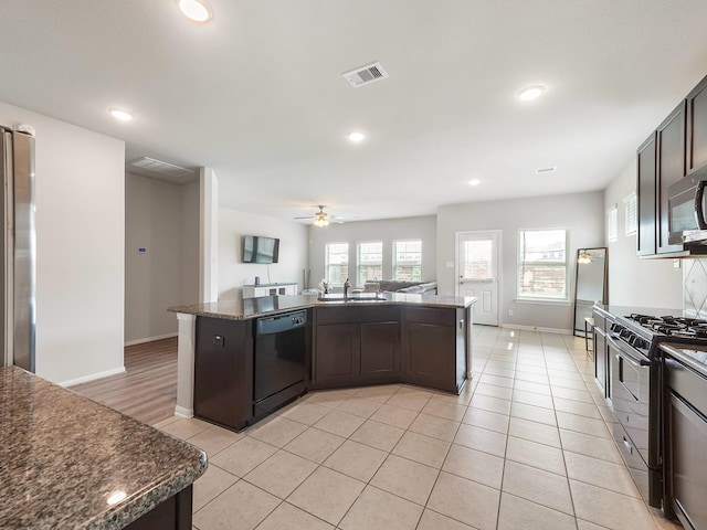 12519 Crathie Dr, Humble, TX 77346 - kitchen with black appliances, dark brown cabinets, open floor plan, recessed lighting, and a center island with sink