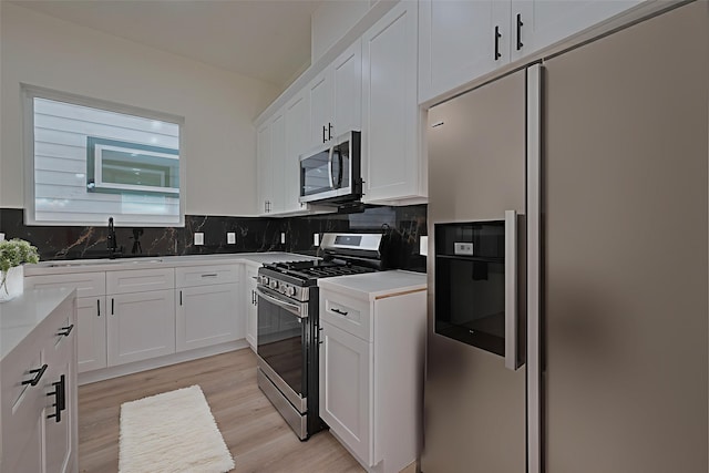 2422 Dalview St, Houston, TX 77091 - kitchen featuring appliances with stainless steel finishes, white cabinets, decorative backsplash, light wood-style flooring, and light countertops