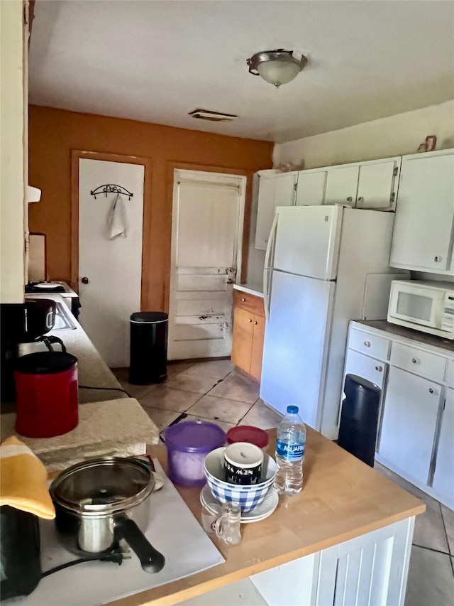 1410 Caplin St, Houston, TX 77022 - kitchen featuring white appliances, light tile patterned floors, light countertops, and white cabinetry