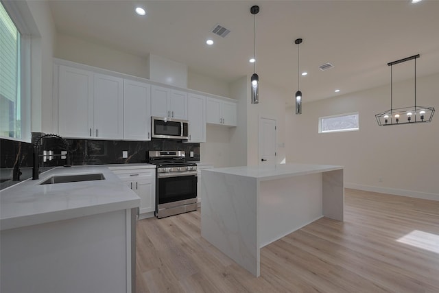 2420 Dalview St, Houston, TX 77091 - kitchen with stainless steel appliances, light wood-style flooring, backsplash, white cabinets, and a kitchen island
