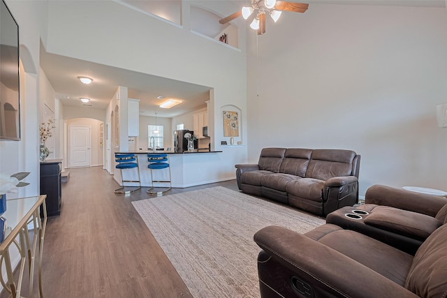 10434 Lake Of The Ozarks Dr, Humble, TX 77396 - living area with wood finished floors, arched walkways, ceiling fan, and a towering ceiling