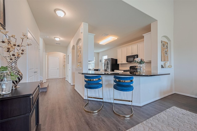 10434 Lake Of The Ozarks Dr, Humble, TX 77396 - kitchen with black microwave, dark wood-type flooring, dark countertops, white cabinetry, and fridge with ice dispenser