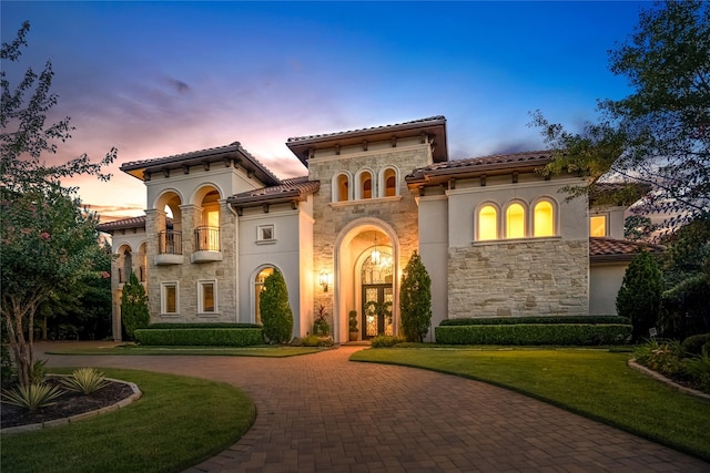 27 S Glenwild Cir, The Woodlands, TX 77389 - mediterranean / spanish-style house with stone siding, curved driveway, a balcony, a front yard, and stucco siding