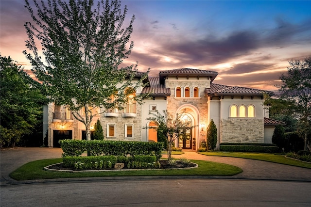 27 S Glenwild Cir, The Woodlands, TX 77389 - mediterranean / spanish home with stone siding, curved driveway, a tiled roof, stucco siding, and a garage