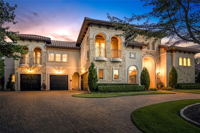 27 S Glenwild Cir, The Woodlands, TX 77389 - mediterranean / spanish house featuring a balcony, curved driveway, stone siding, a tiled roof, and an attached garage