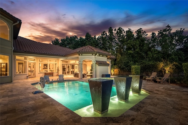 27 S Glenwild Cir, The Woodlands, TX 77389 - pool at dusk featuring french doors, a patio area, and an outdoor pool