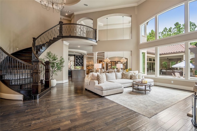27 S Glenwild Cir, The Woodlands, TX 77389 - living room featuring a towering ceiling, stairs, a chandelier, crown molding, and wood finished floors