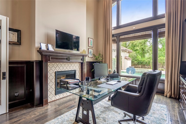 27 S Glenwild Cir, The Woodlands, TX 77389 - office space with wood-type flooring, a tiled fireplace, and a towering ceiling