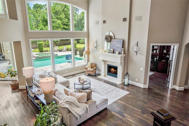 27 S Glenwild Cir, The Woodlands, TX 77389 - living area with a towering ceiling, a lit fireplace, and dark wood finished floors