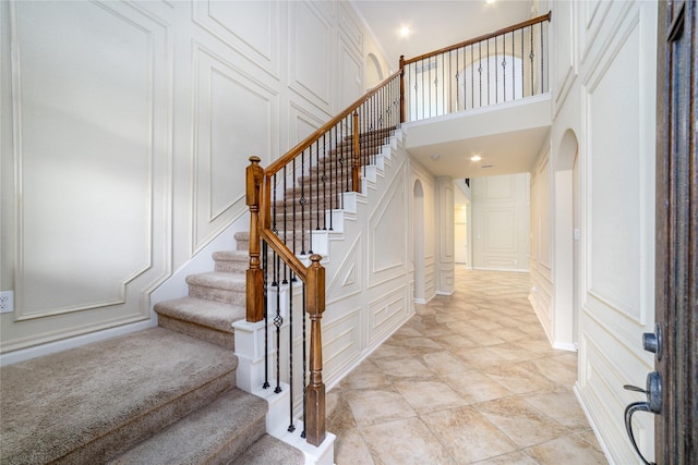 19503 S Coral Honeysuckle Loop, Cypress, TX 77433 - stairs featuring a decorative wall, a high ceiling, arched walkways, and recessed lighting