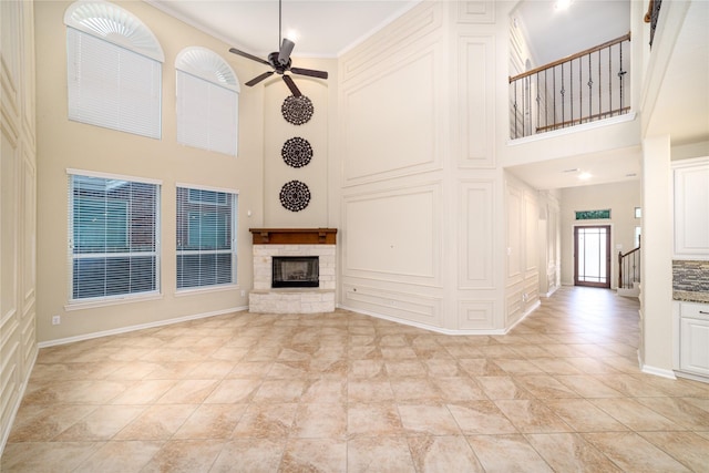 19503 S Coral Honeysuckle Loop, Cypress, TX 77433 - unfurnished living room with a high ceiling, a stone fireplace, a ceiling fan, stairs, and a decorative wall