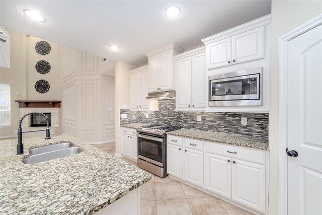 19503 S Coral Honeysuckle Loop, Cypress, TX 77433 - kitchen with stainless steel appliances, under cabinet range hood, tasteful backsplash, light tile patterned flooring, and white cabinetry